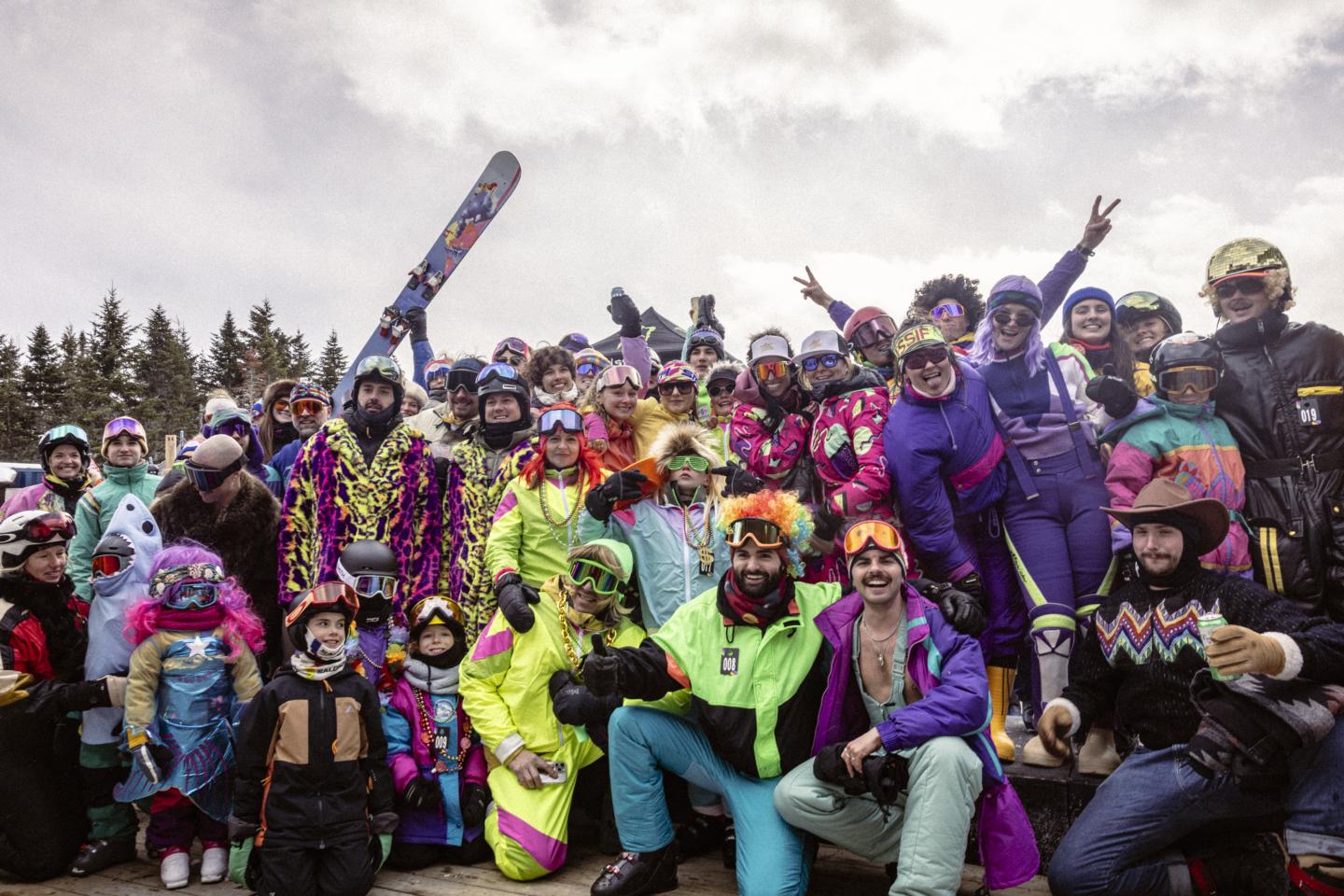 Groupe de skieurs et snowboardeurs en tenues colorées posant dans la neige.
