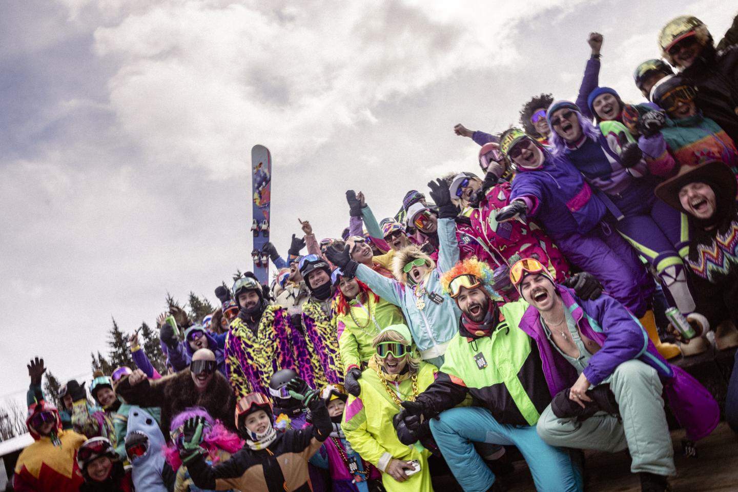 Foule en costumes colorés célébrant un festival en plein air sous un ciel nuageux.