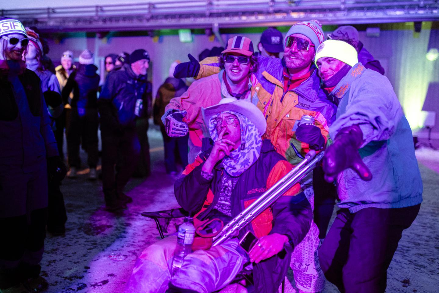 Personnes déguisées autour d’un fauteuil roulant éclairé en violet lors d’une soirée.
