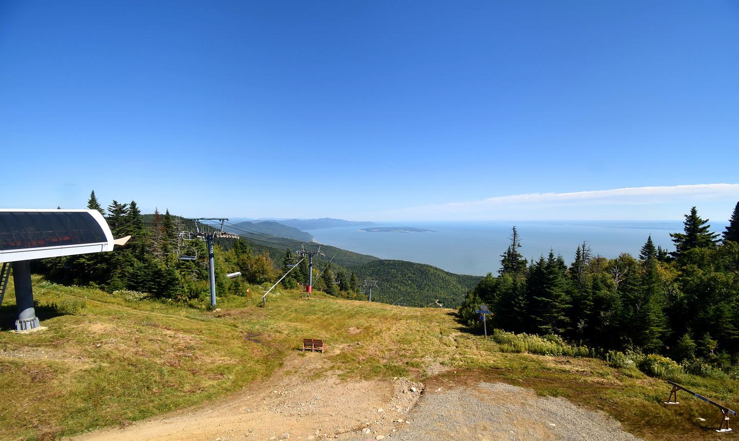 Vue panoramique sur des collines boisées sous un ciel bleu.