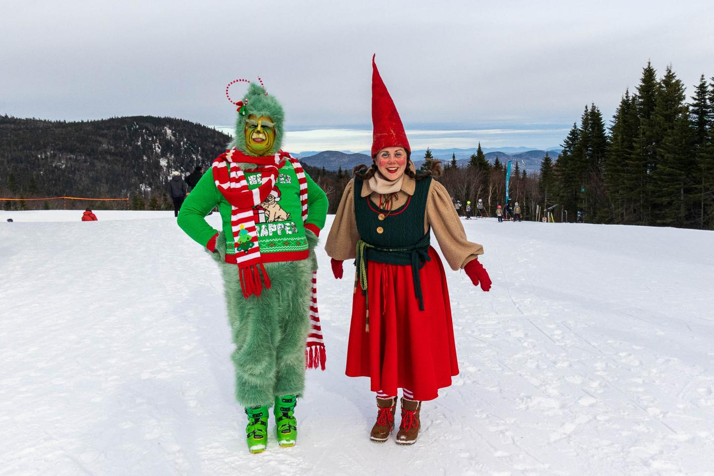 Deux personnes déguisées en lutin et en gnome sur une piste enneigée.